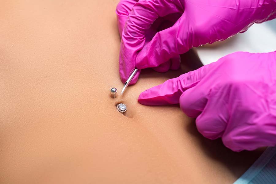 Belly button piercing. The beautician does the piercing procedur